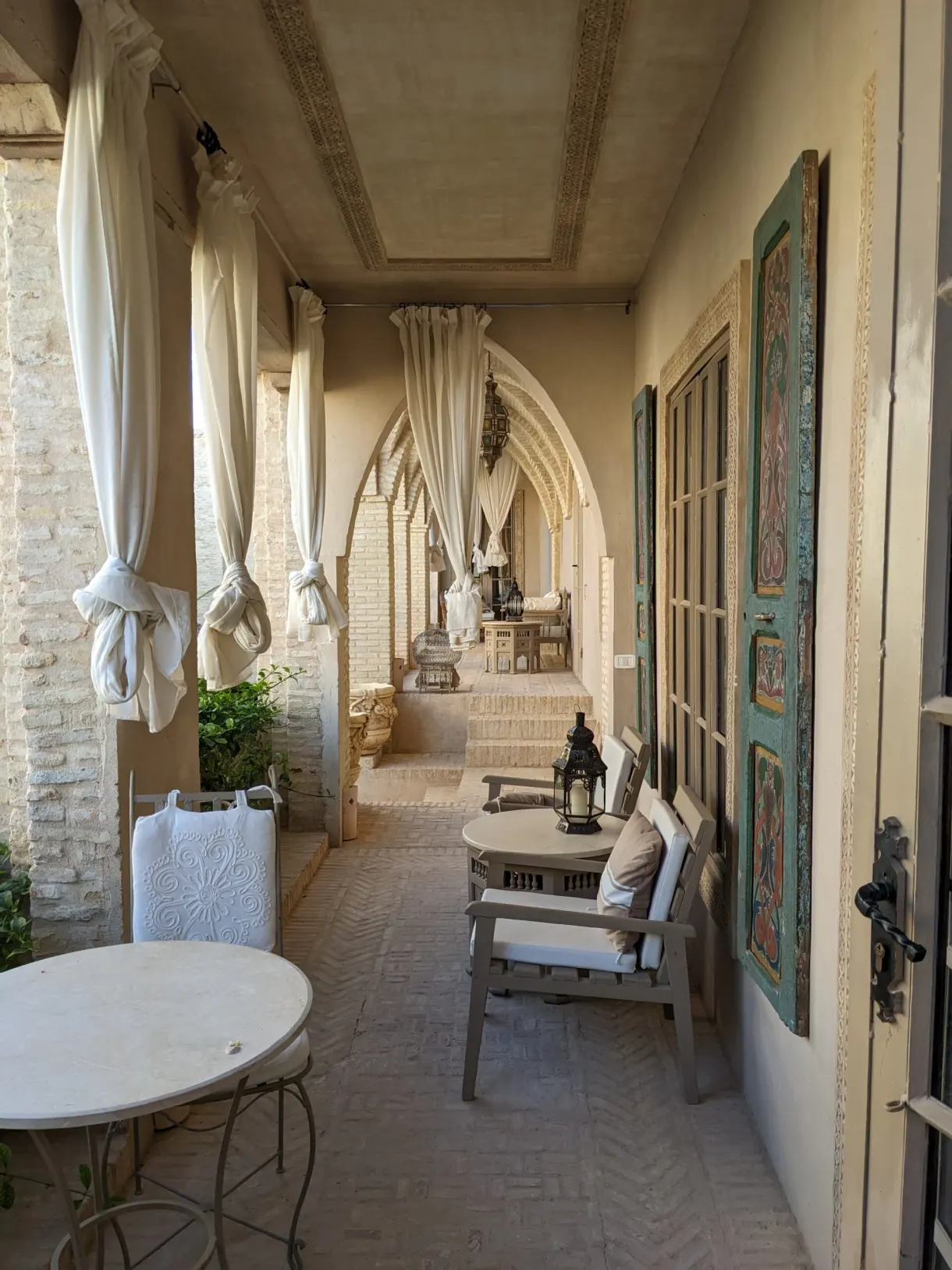 Galerie à arcades et rideaux blancs de la maison d'hôtes de Maurizio à Tozeur