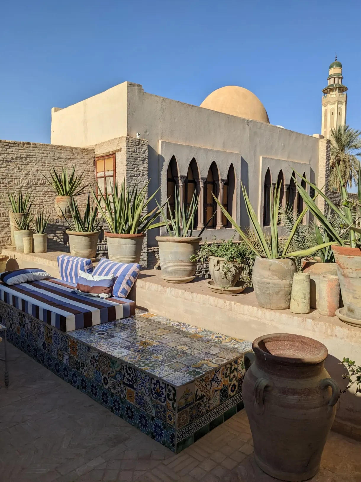 Toit-terrasse de la maison de Maurizio à Tozeur, banquette en zellige et minaret au loin
