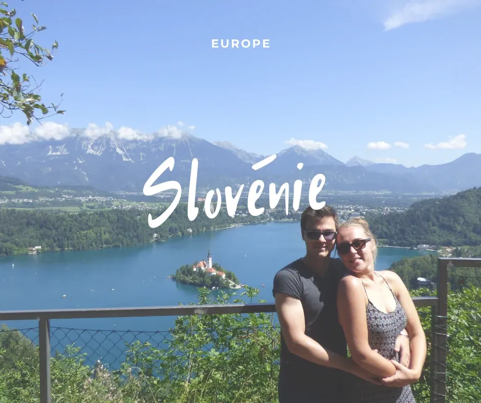 Couple devant un lac à l'île boisée et aux montagnes enneigées