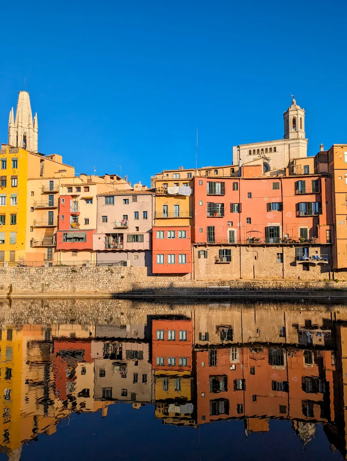 Colourful houses in Girona reflected in the Onyar, with the cathedral in the background