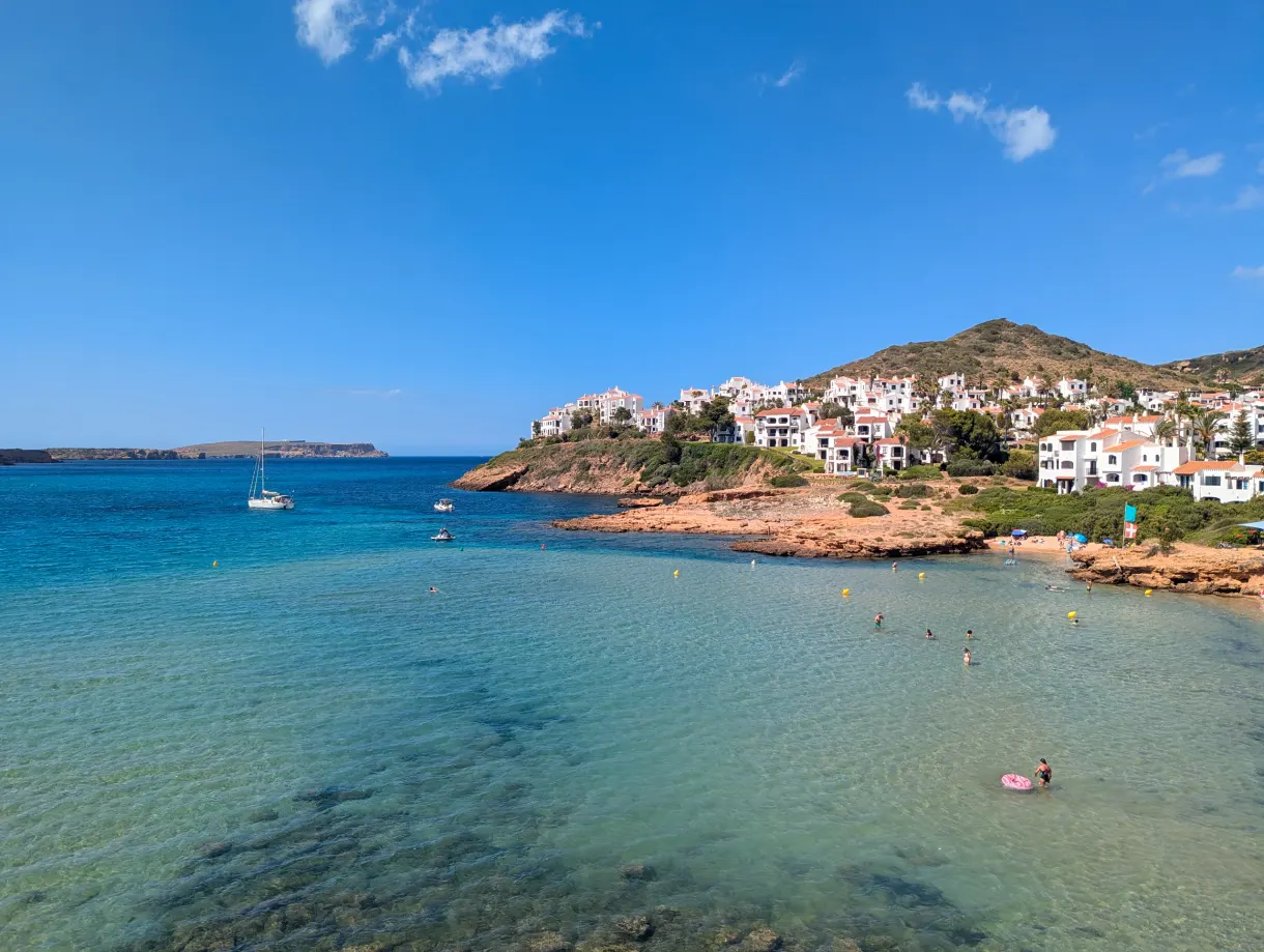 White village overlooking a turquoise cove in Menorca