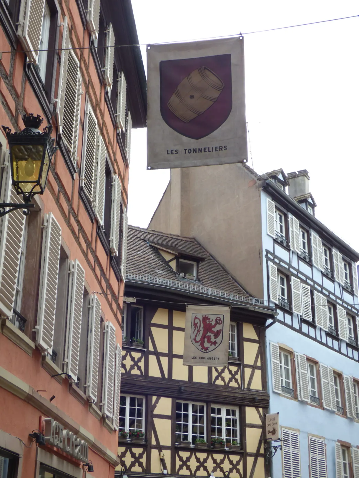Painted cooper's sign hanging in front of a pink facade