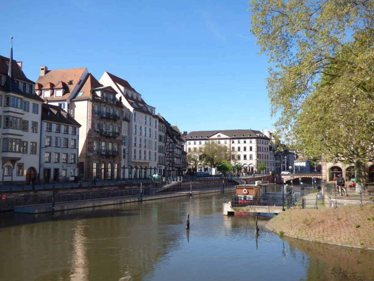 Wide river between two quays of apartment buildings, small boat in the distance