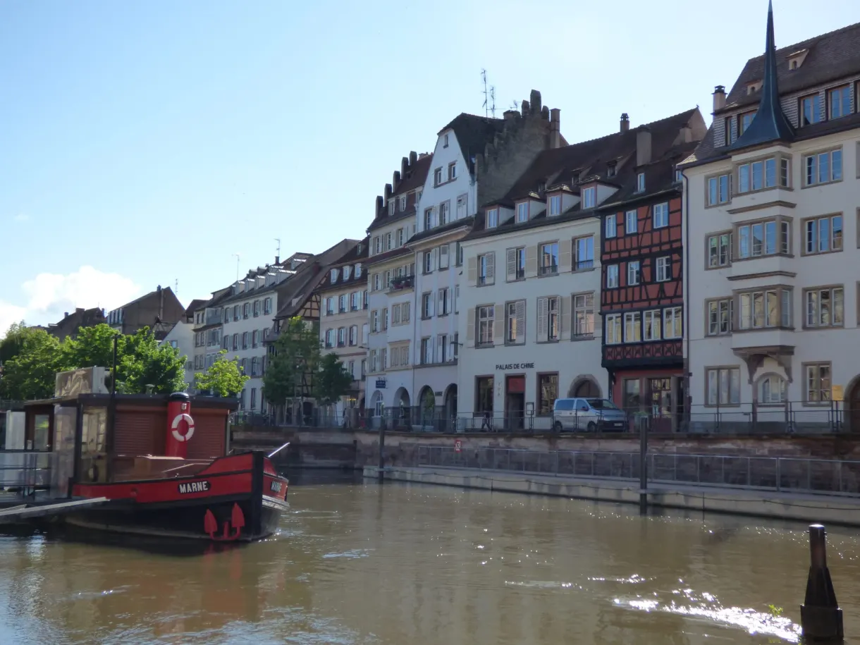 Red barge moored along the quay with its pale facades