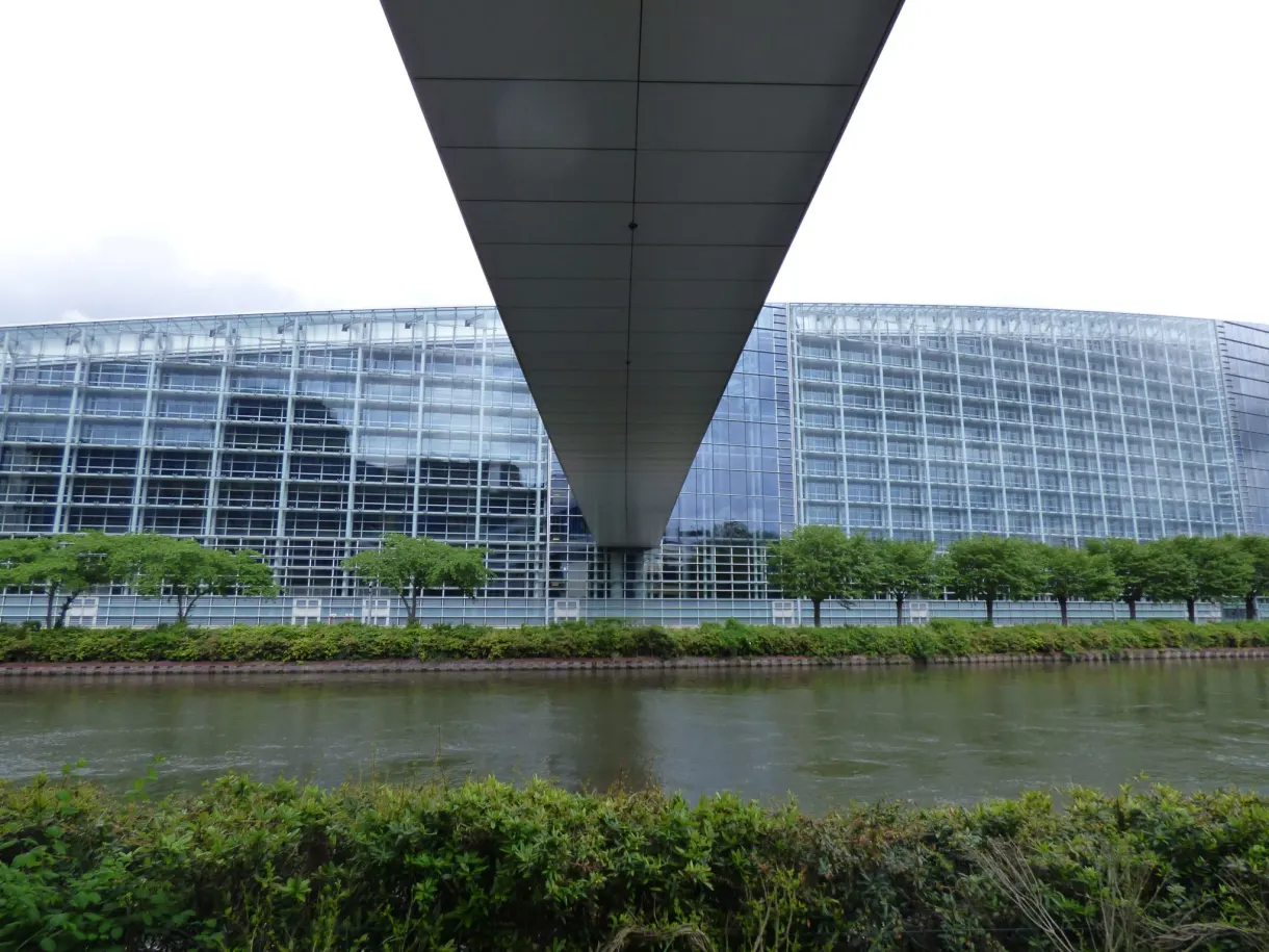 Curved glass buildings by the water under a grey sky