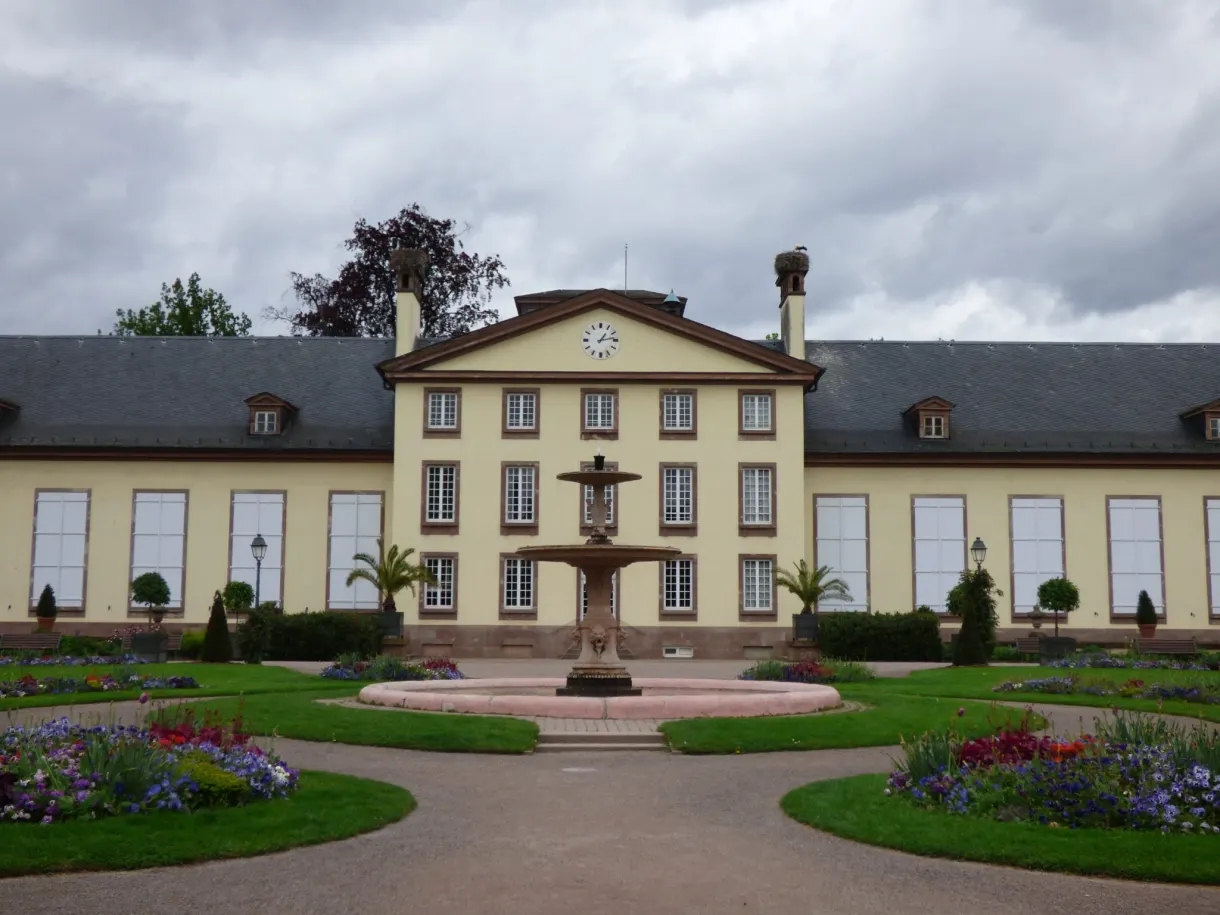 Yellow neoclassical building and round fountain at the centre of the park