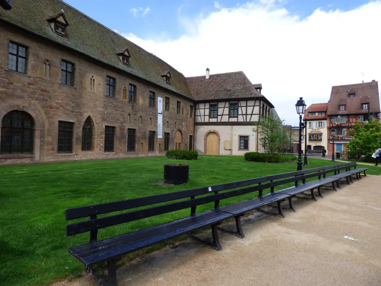 Enclosed courtyard lined with old buildings and rows of benches
