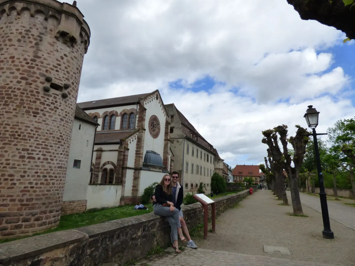 Round tower of the ramparts and an old building, women sitting nearby