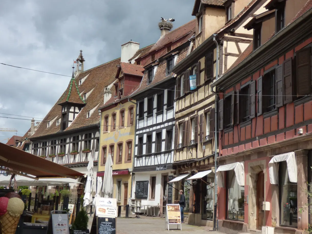 Pedestrian street with terraces and shop windows below the old facades