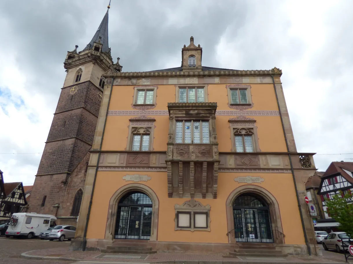 Ochre town hall with a carved oriel, belfry just behind