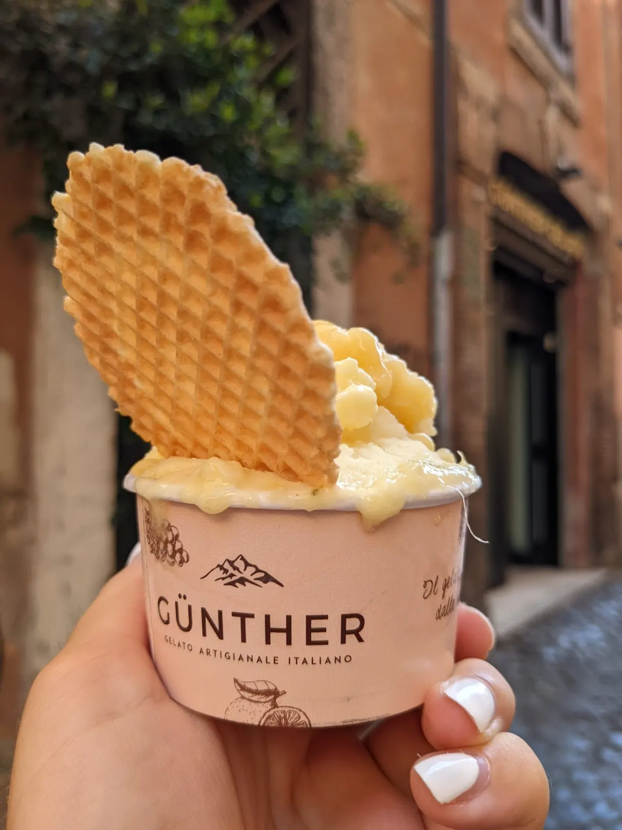 Pot de glace surmonté d'une large gaufrette tenu à la main