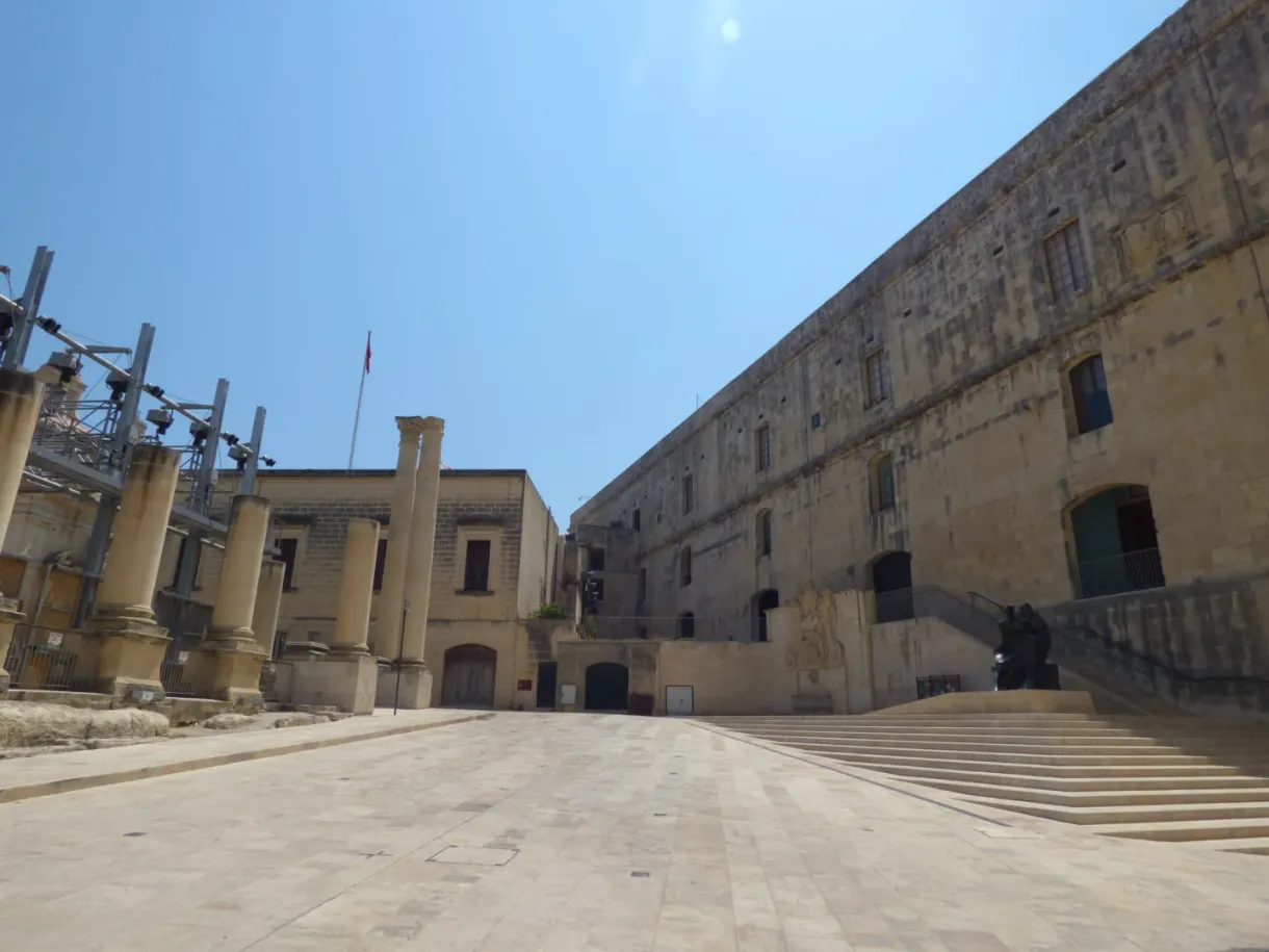 Vast paved esplanade in front of a long palace of golden stone