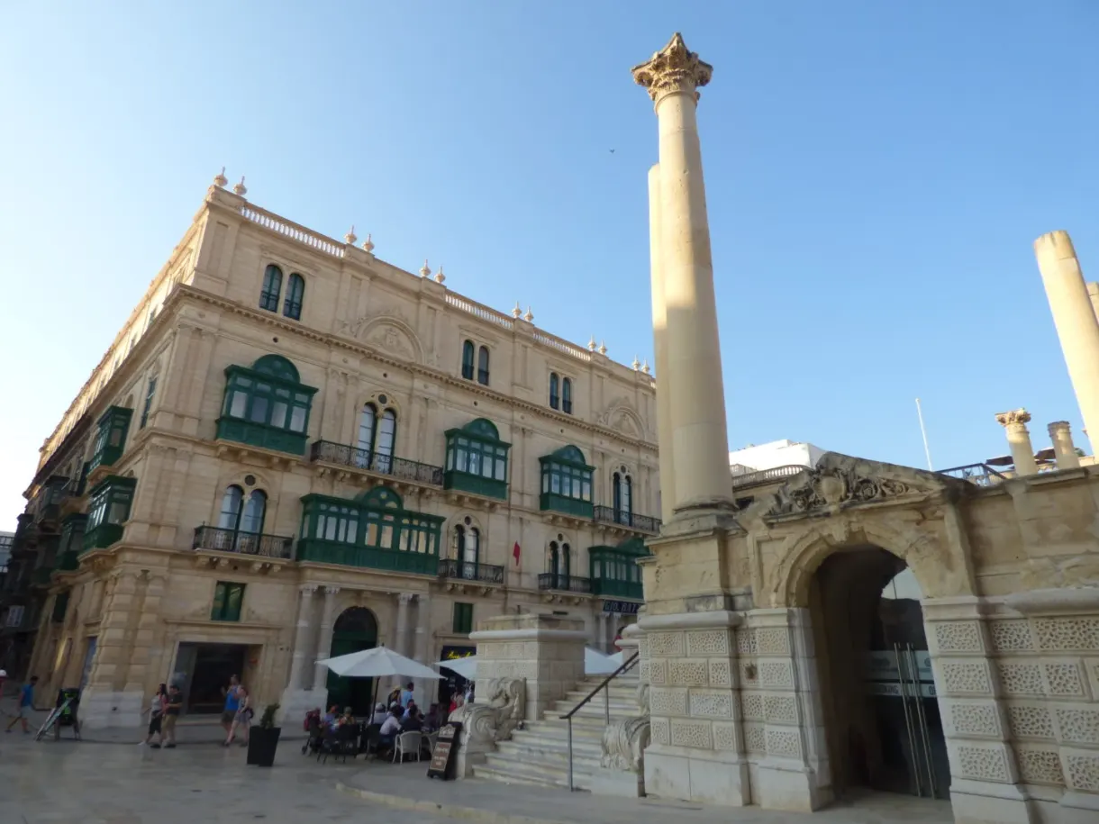 Palace with green balconies and a stone column on the square