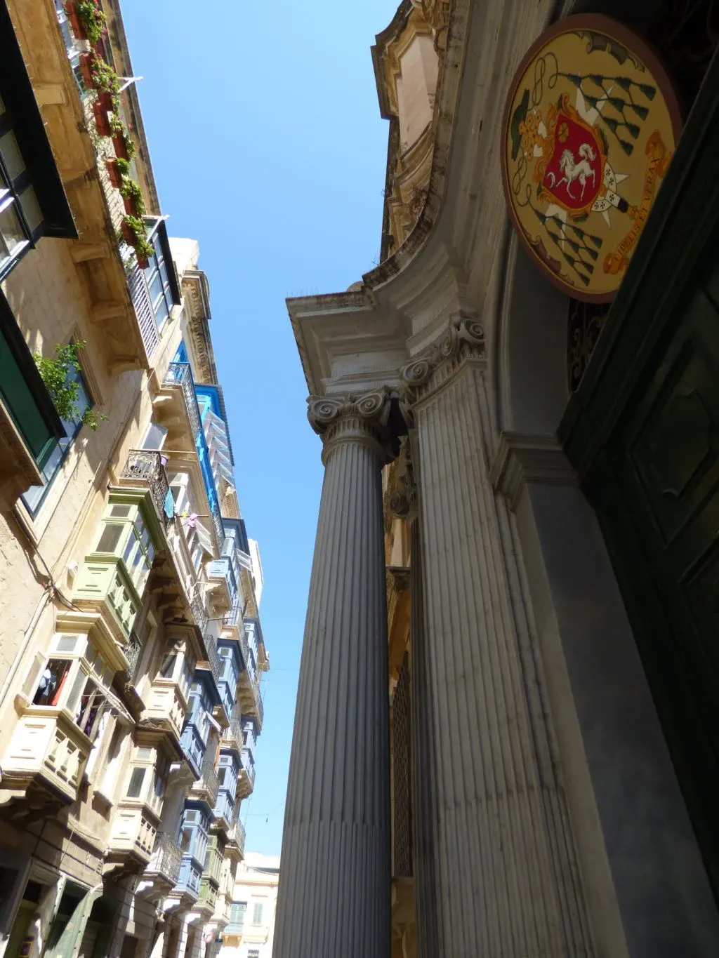 Column and carved coat of arms seen from below between the facades