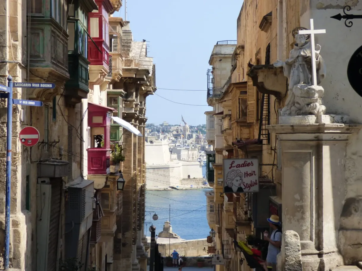 Street sloping down to the harbour, a stone cross in the foreground