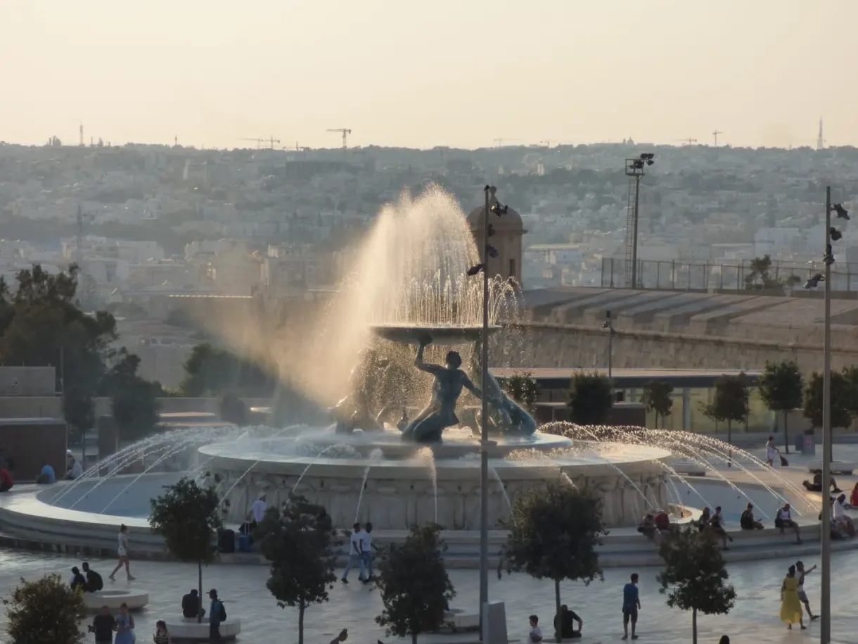 Jets of the fountain blown by the wind in front of the city