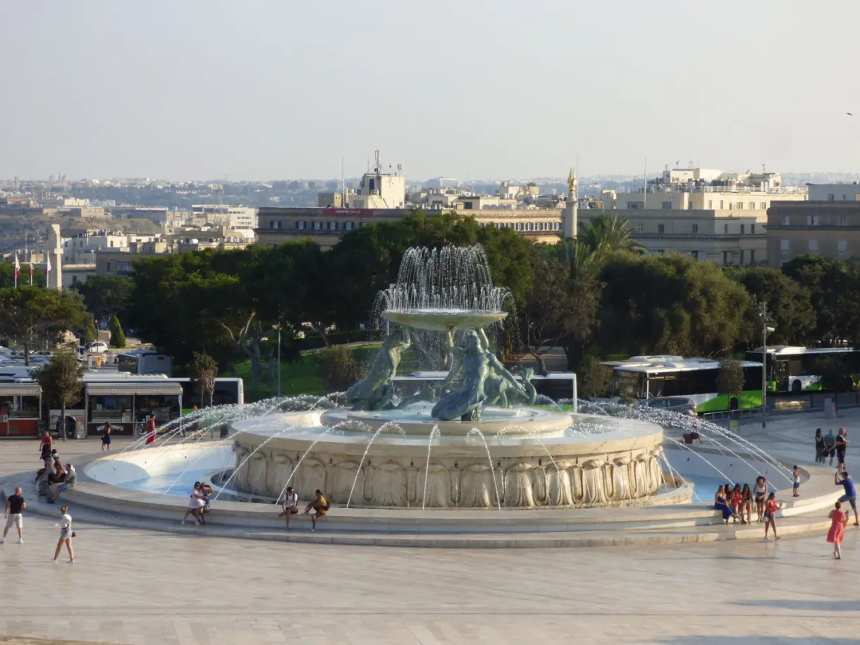 Circular basin of the fountain and passers by on the esplanade