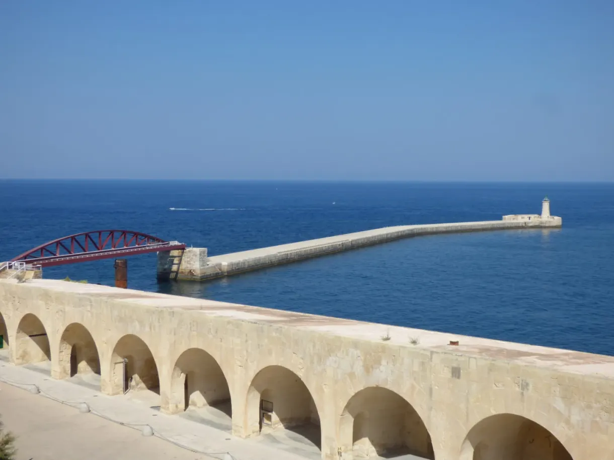 Red footbridge and jetty closing the harbour, lighthouse at the end