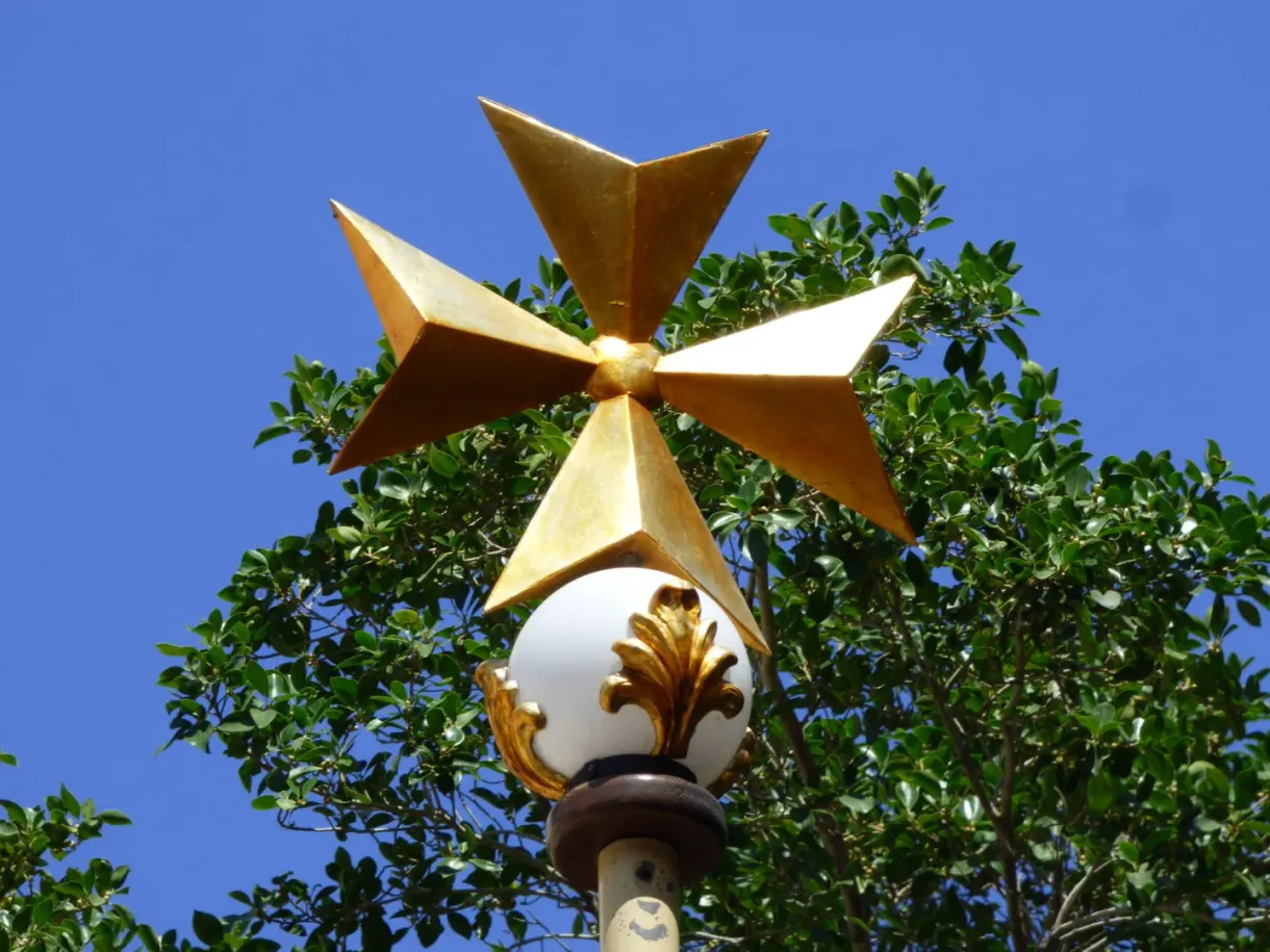 Gilded Maltese cross at the top of a street lamp