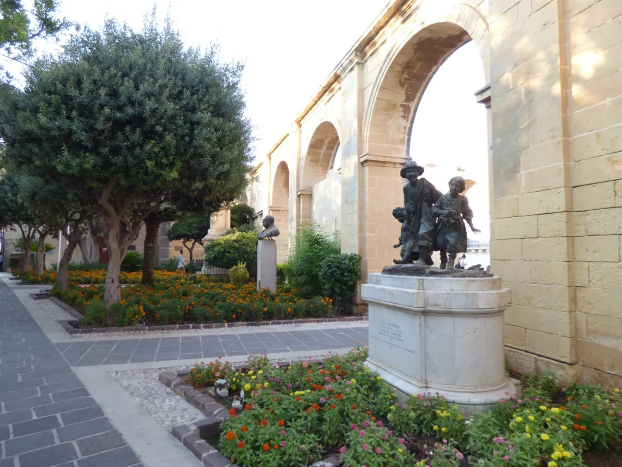 Bronze statue and flower beds beneath the arcades