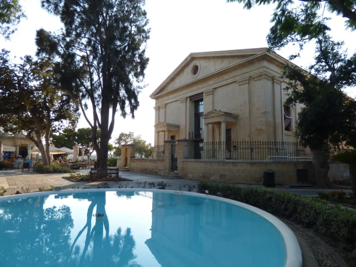 Turquoise pool reflecting the trees in front of a neoclassical temple