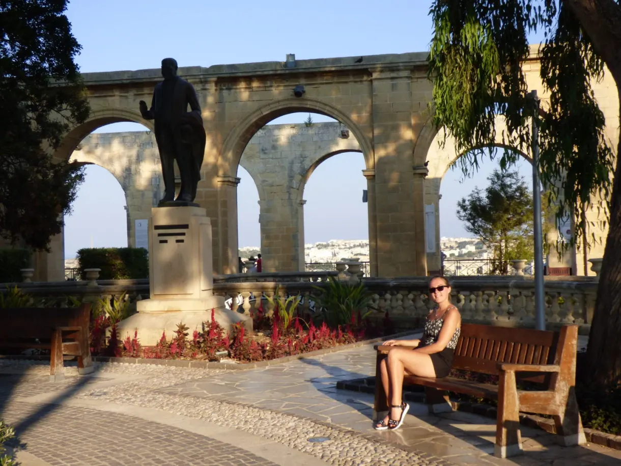 Woman sitting on a bench in the shade of the arcades