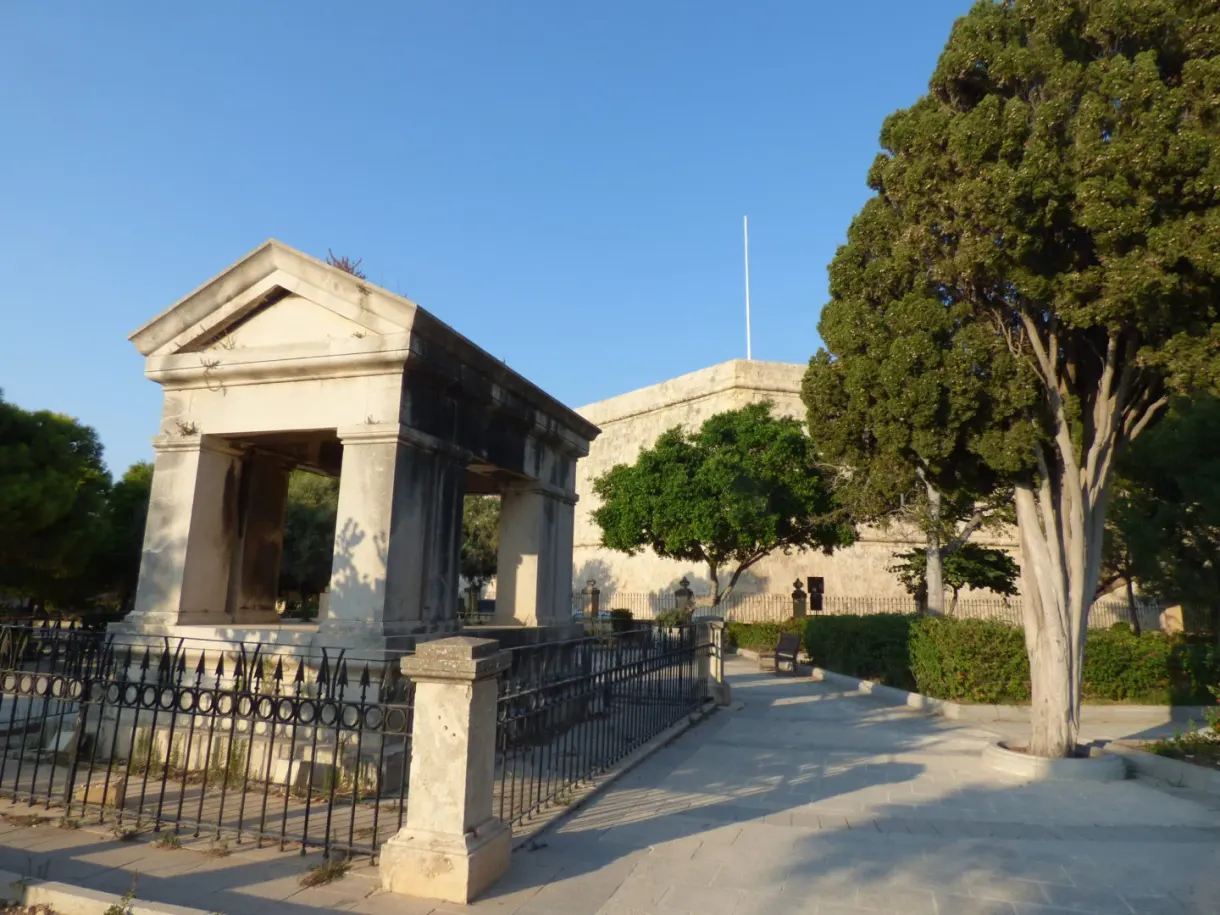 Neoclassical monument surrounded by a railing and tall trees