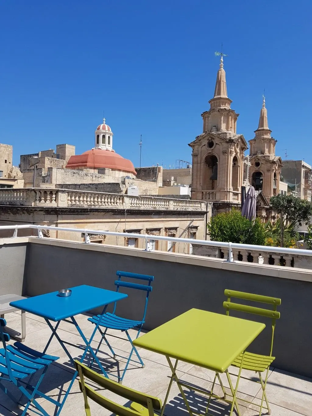 Green and blue chairs in front of the city's bell towers