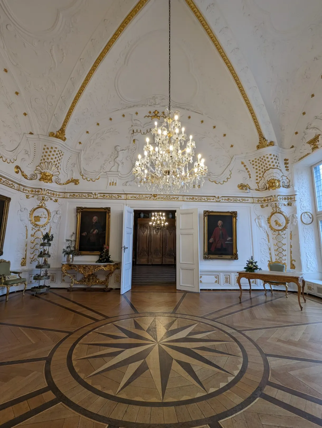 Wooden parquet rosette beneath a chandelier in a white hall