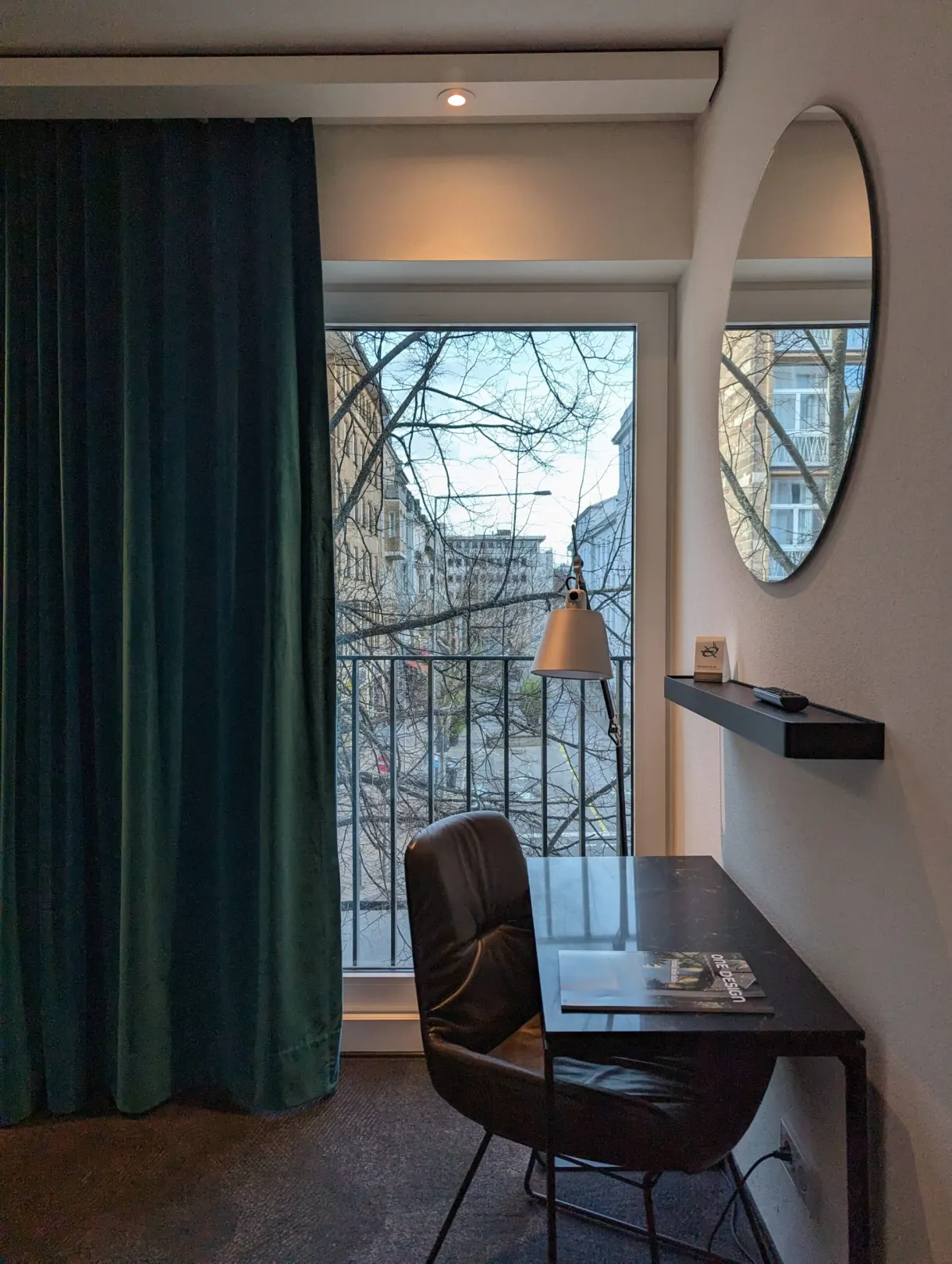 Desk nook, round mirror and window overlooking neighbouring rooftops