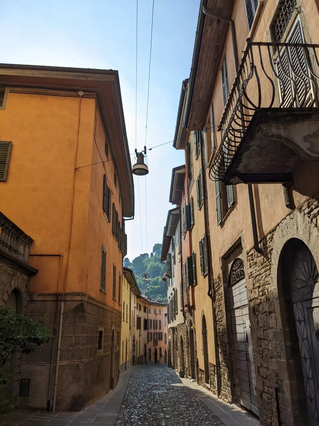Cobbled street heading downhill between orange and beige facades