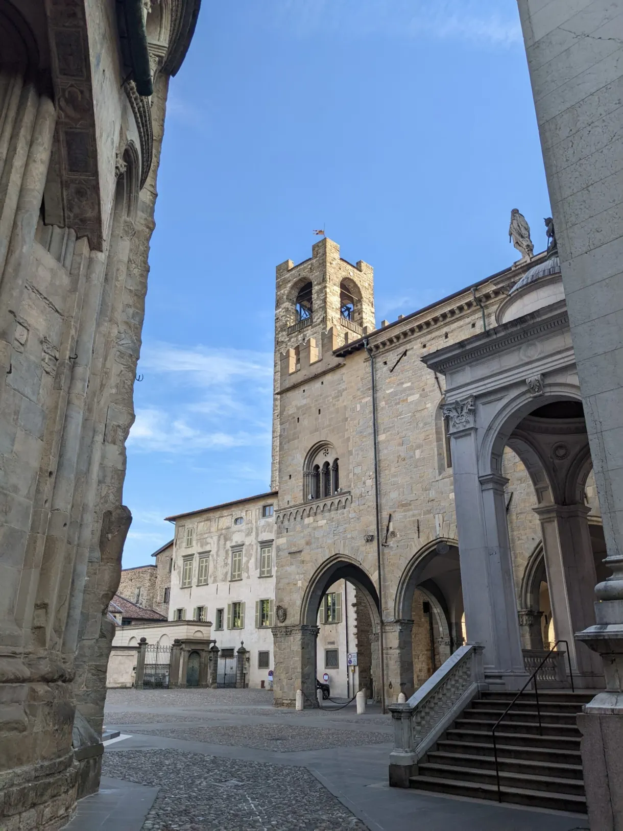 Crenellated tower glimpsed from the arcades of a square