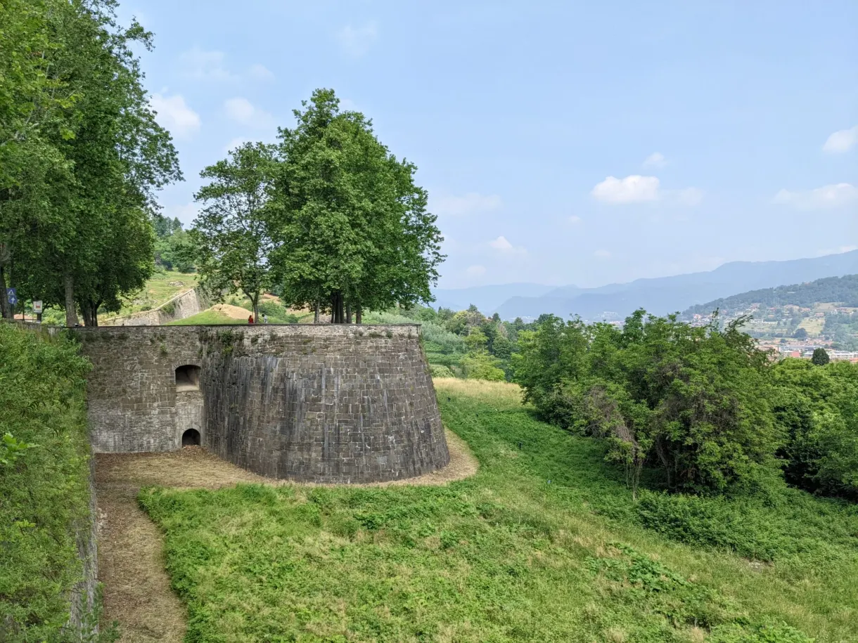 Rounded bastion emerging from a grassy slope planted with trees