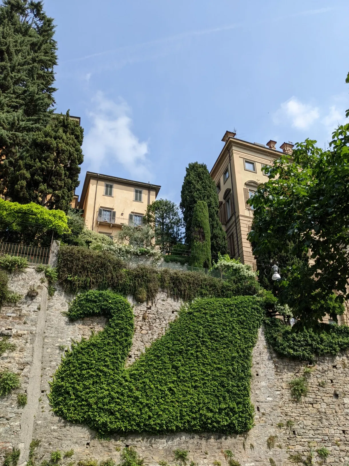 Path climbing between stone walls and yellow houses