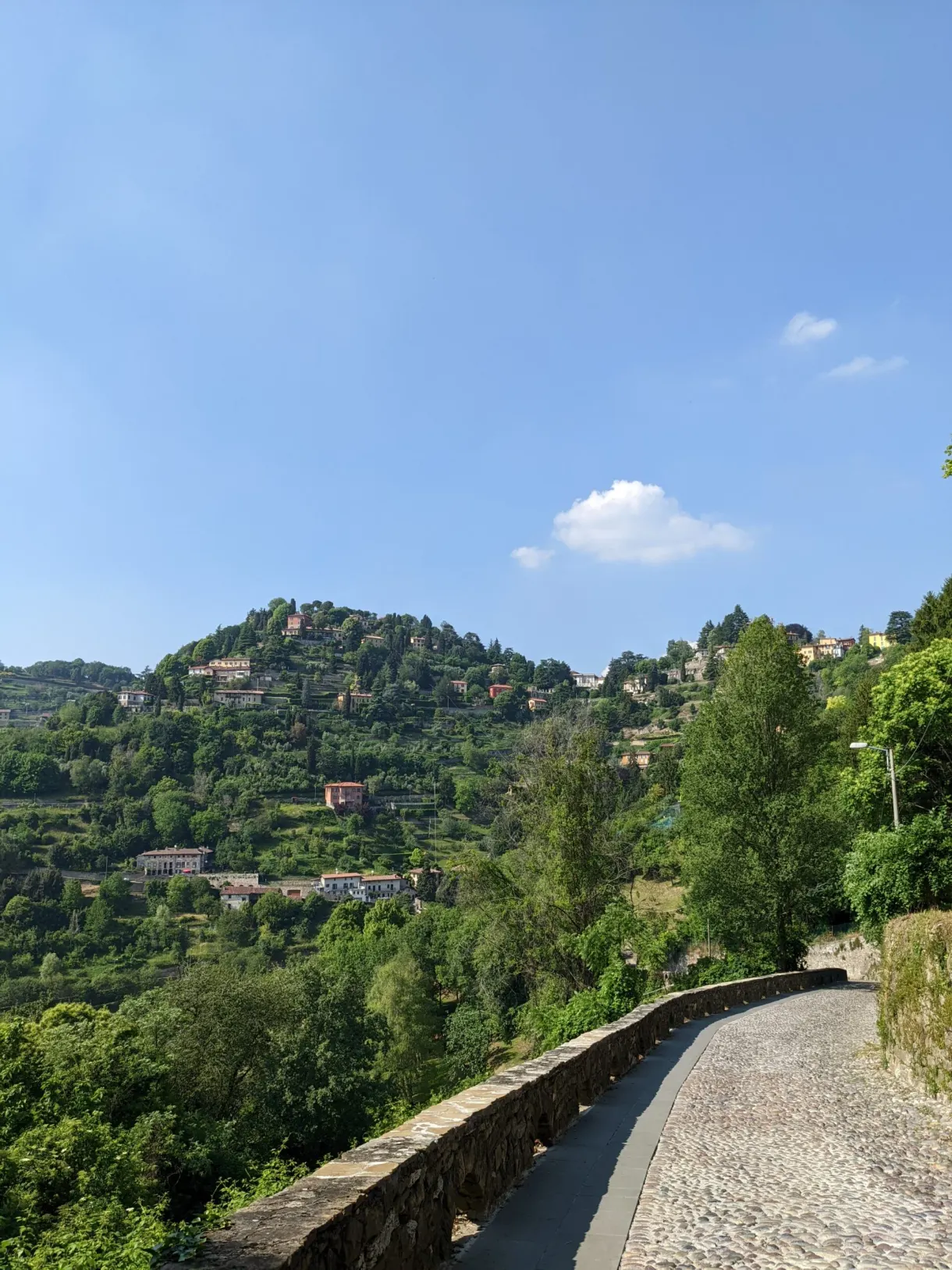 Paved path running along a wall facing an inhabited hill