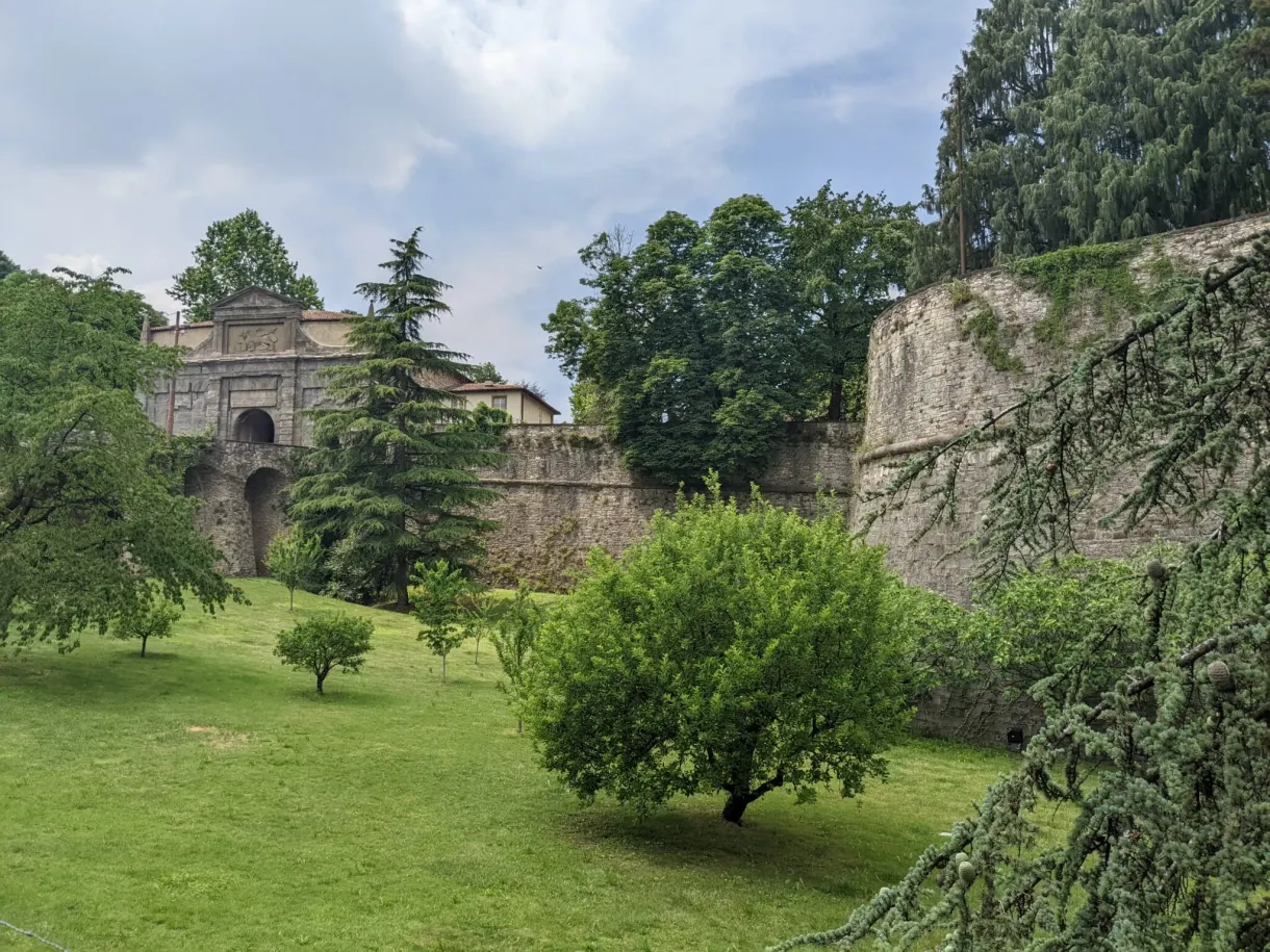 Fortified gate at the end of a lawn planted with trees