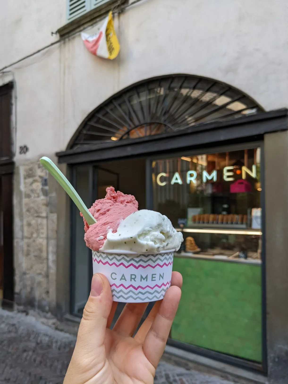 Two-flavour ice cream in front of an ice cream shop window