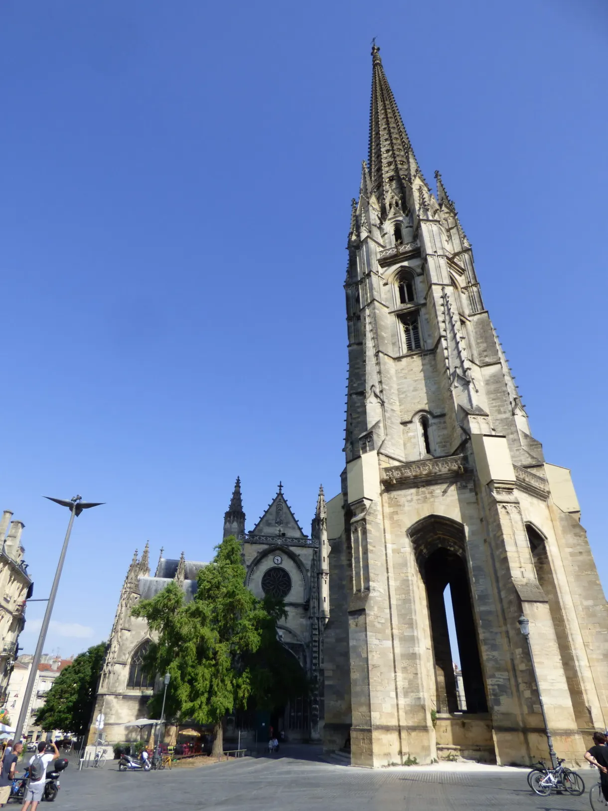Clocher isolé en pierre claire et son église gothique sous un ciel bleu