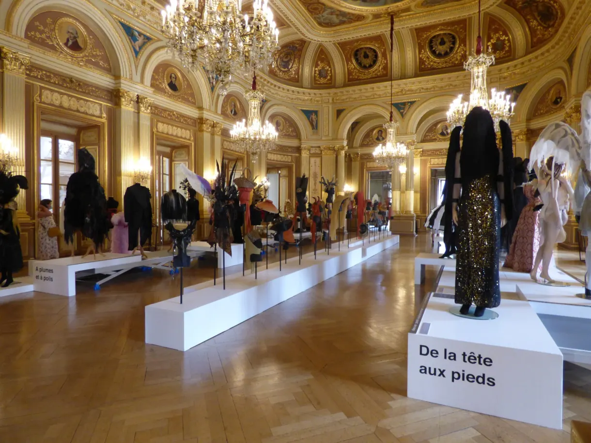 Costumes de scène exposés dans un salon doré à lustres de cristal