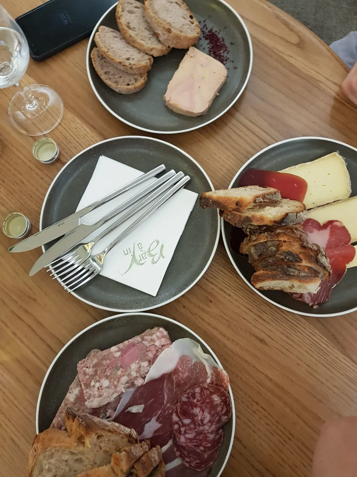 Assiettes de charcuterie, fromage et foie gras posées sur une table de bois