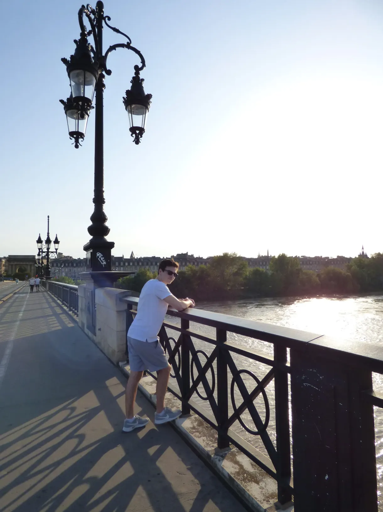 Homme accoudé au garde-corps du pont dans la lumière du soir