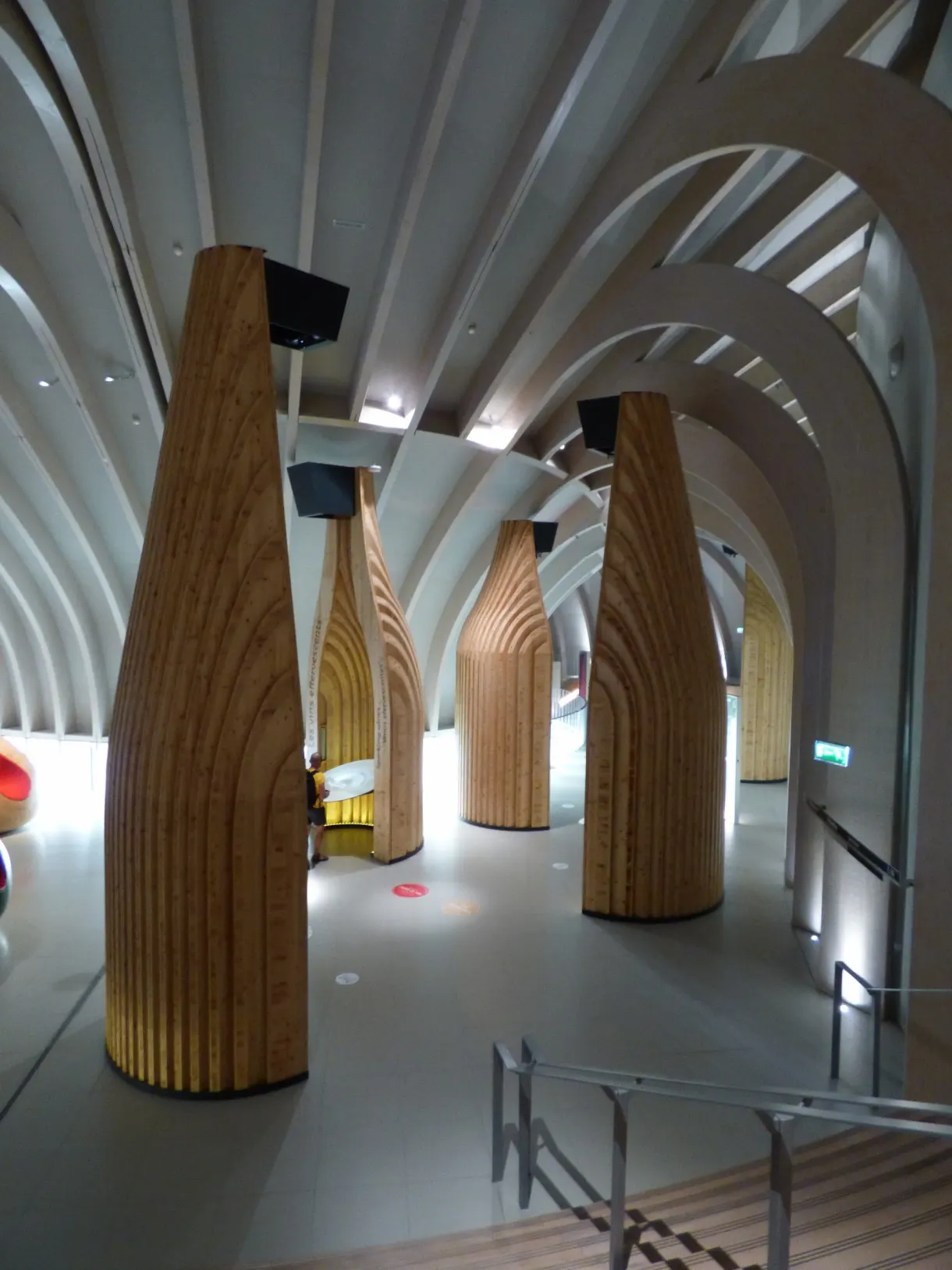 Colonnes de bois évasées sous une voûte blanche dans un musée