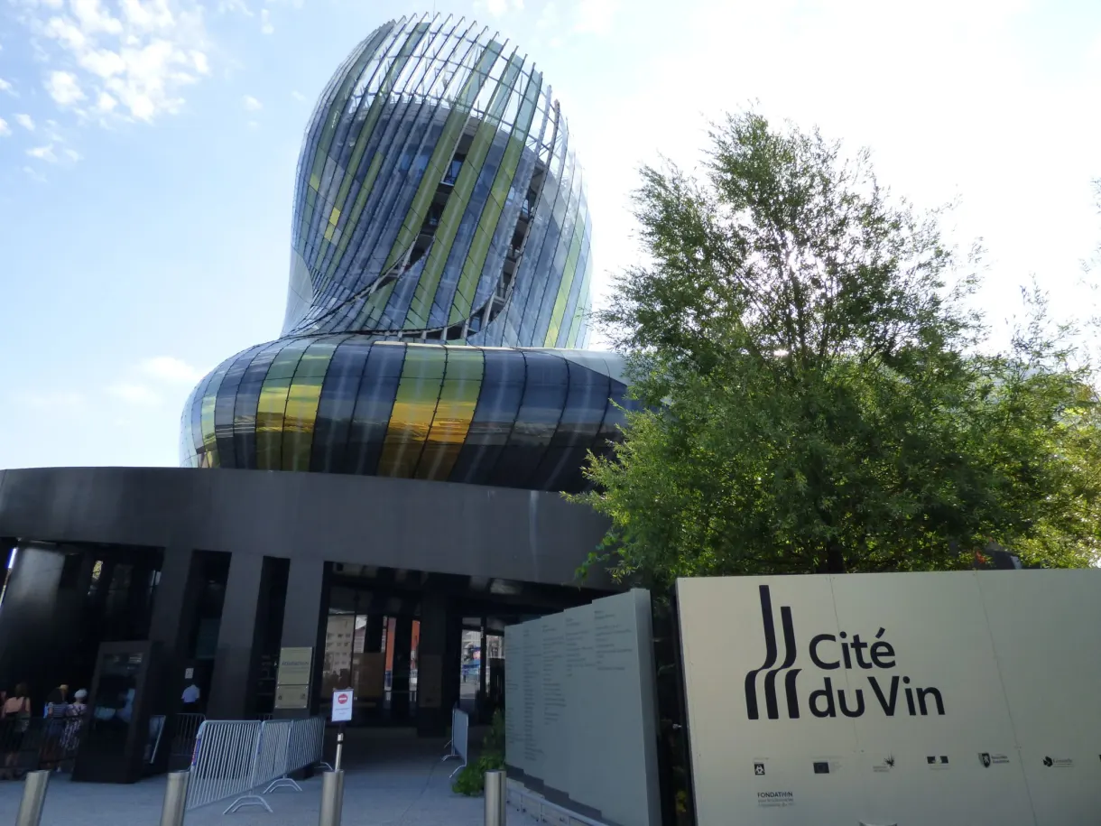 Entrée vitrée de la Cité du Vin et son panneau à l'enseigne dorée