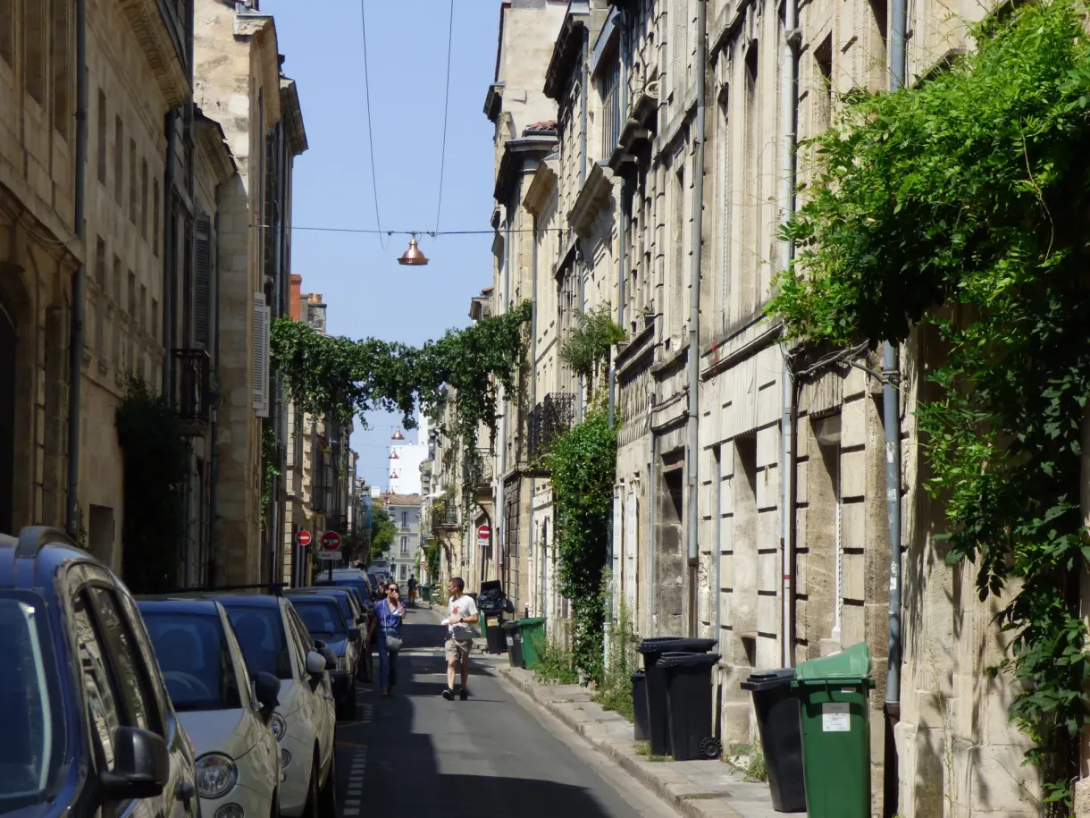 Rue en pente bordée de façades de pierre et de plantes grimpantes