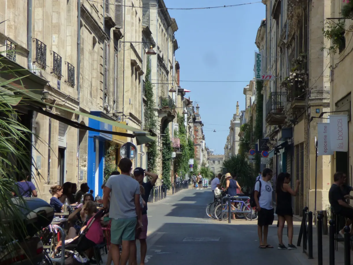 Rue piétonne animée, terrasses et cyclistes un jour d'été