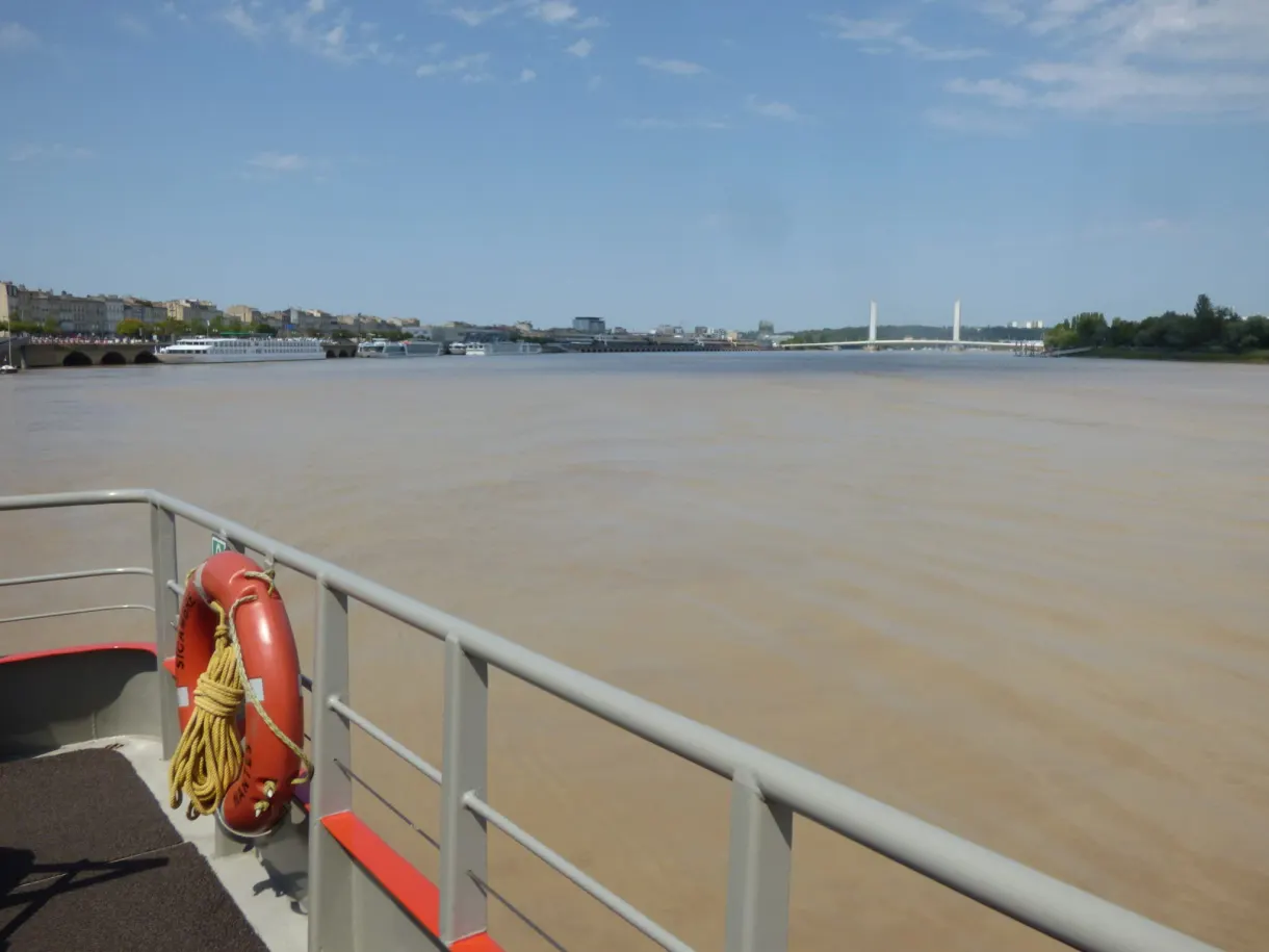 Bouée orange sur le bastingage face à un fleuve couleur limon