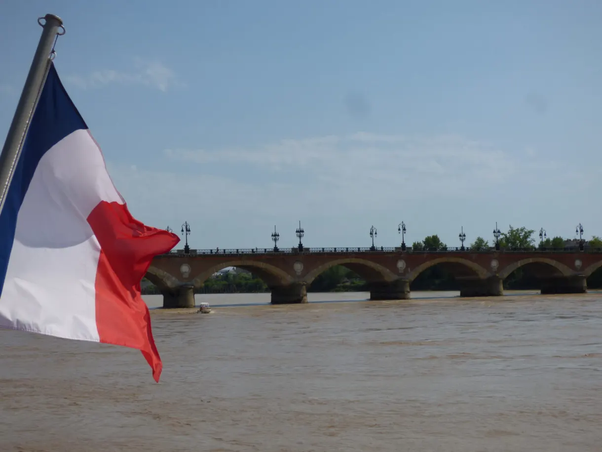 Drapeau tricolore claquant au vent devant les arches du pont