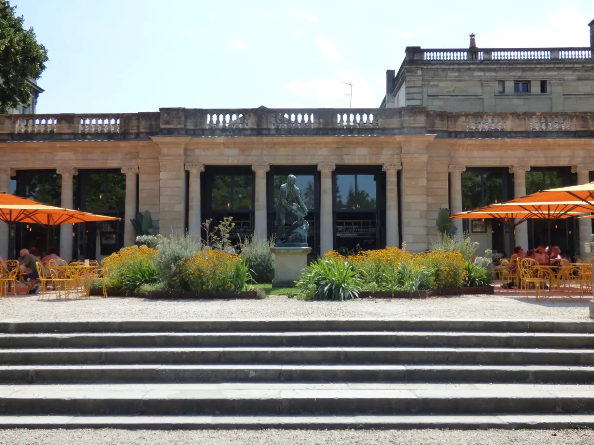 Guinguette à colonnade et parasols orange en haut d'un escalier