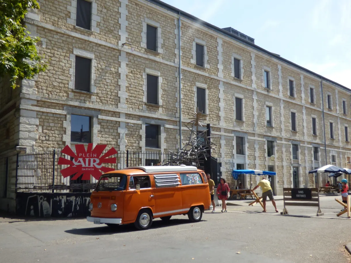 Combi Volkswagen orange garé dans la cour d'anciennes casernes
