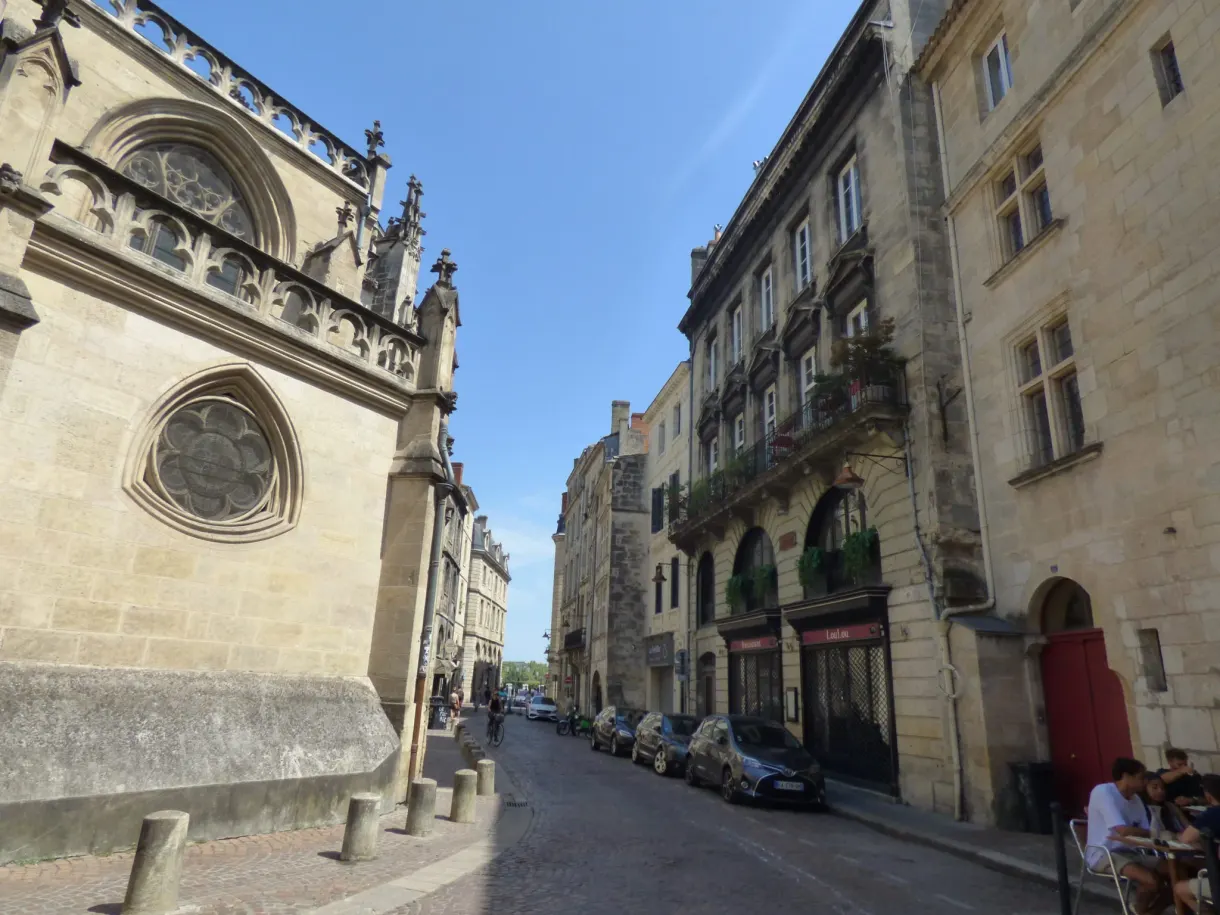 Flanc d'église et sa rosace au bord d'une rue en pente